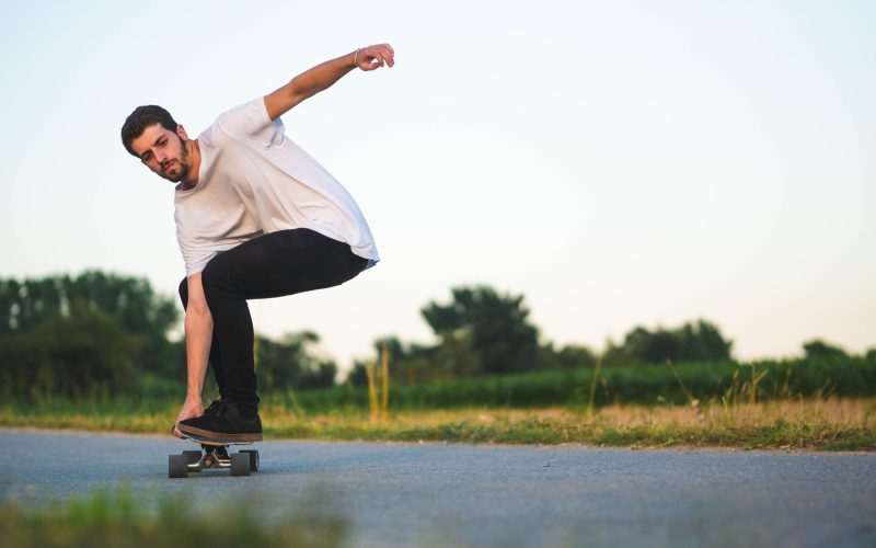 A shallow focus shot of a young handsome male riding a skateboard